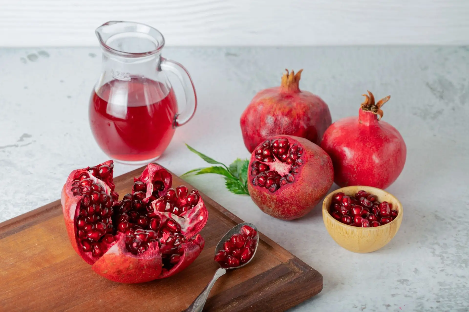 Whole, sliced pomegranates on wood.