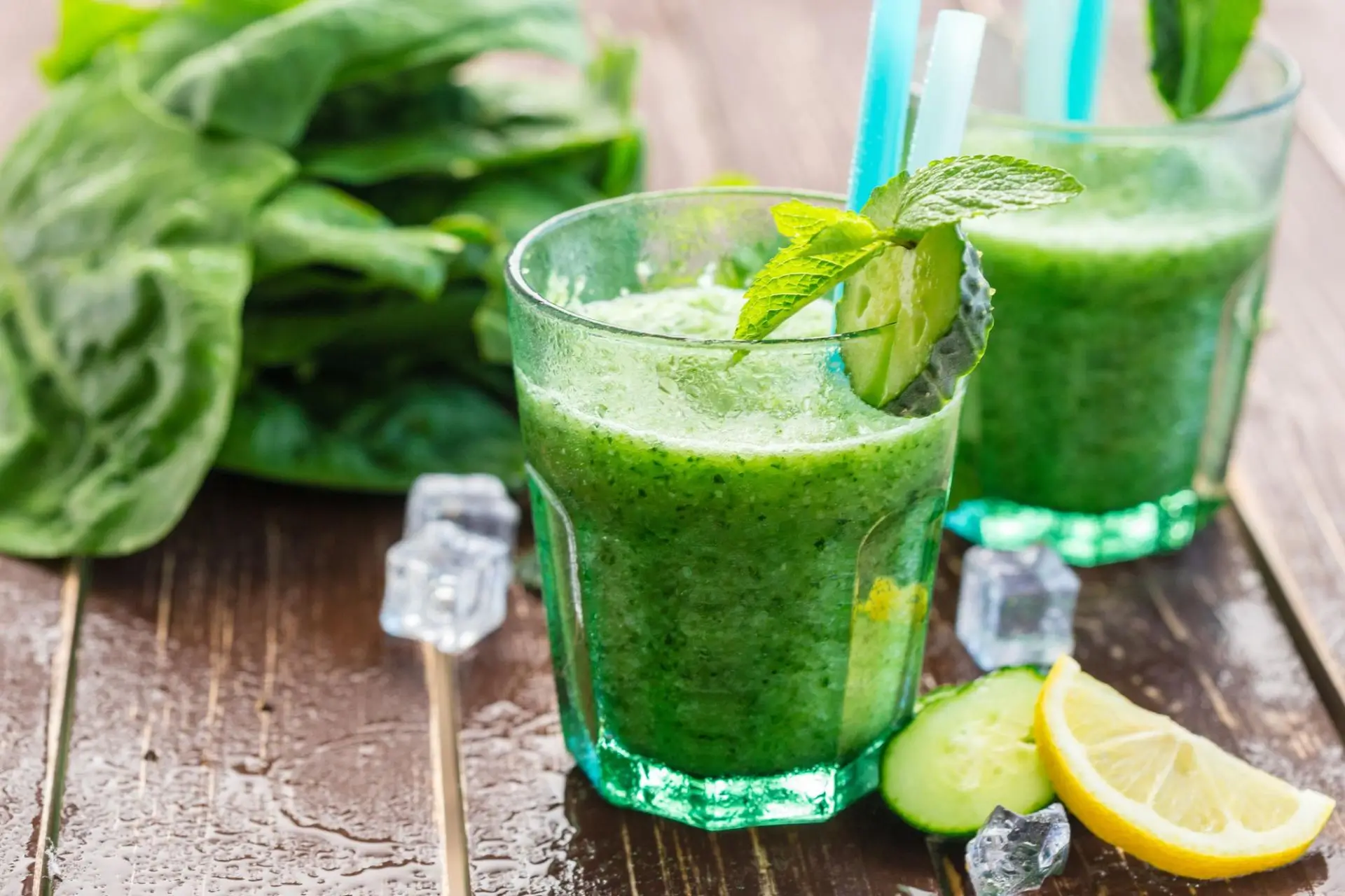 Green vegetable smoothie in a clear glass on a wooden table.