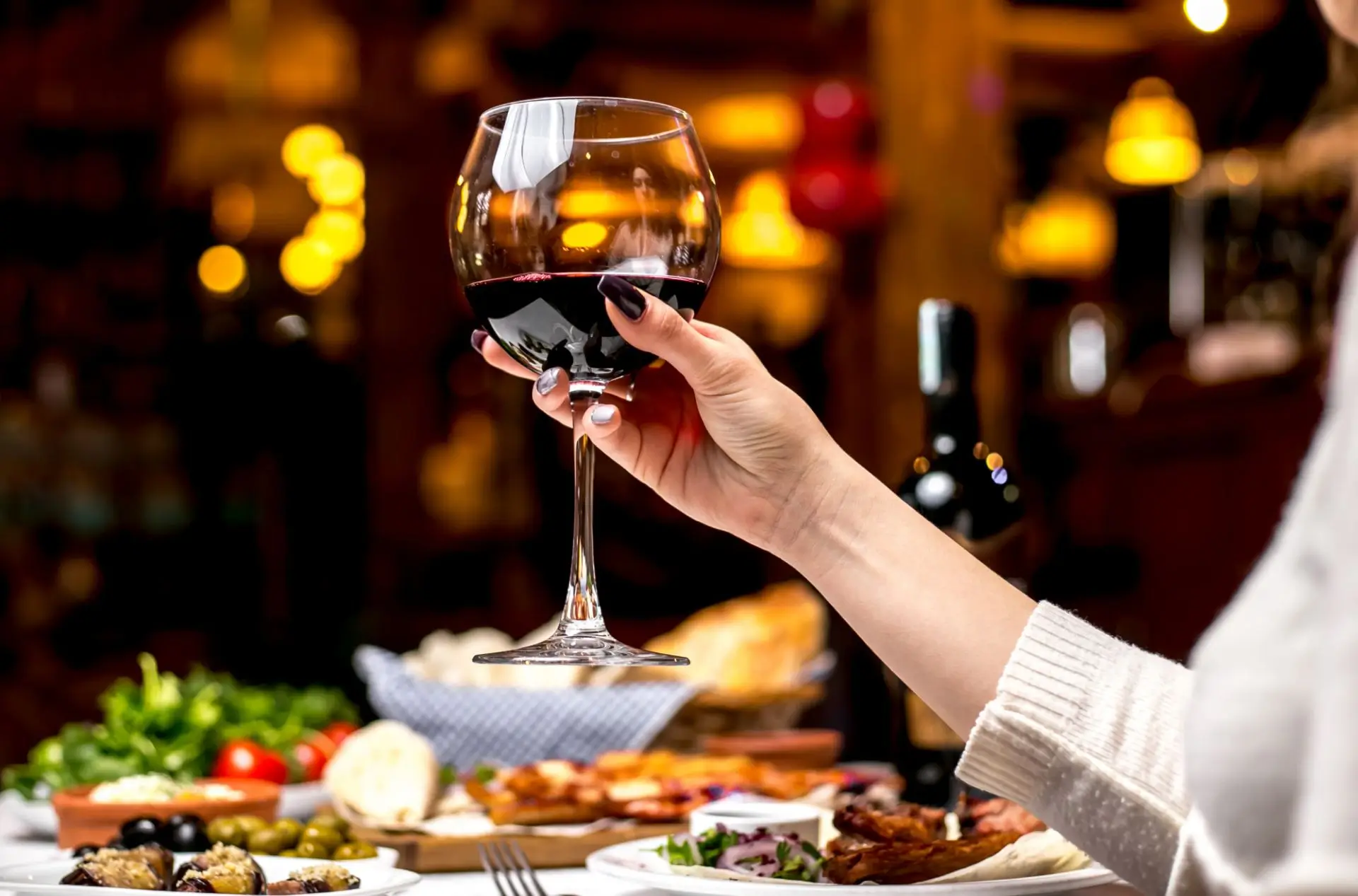 Woman drinking red wine, side view.